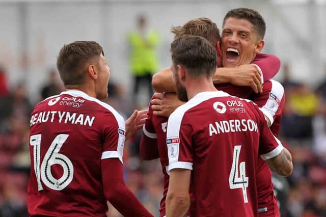 STUNNING STRIKE - Alex Revell and his team-mates congratulate Matt Taylor after his stunning free-kick fired the Cobblers into a 3-0 lead versus Milton Keynes Dons (Picture: Sharon Lucey)