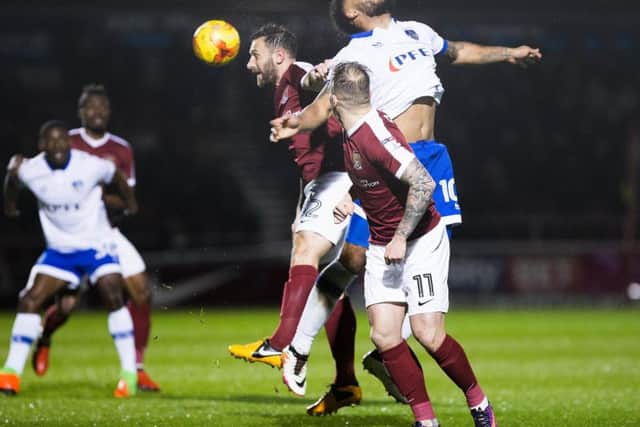 Neal Eardley wins this aerial battle during the Cobblers' clash with Oldham (Pictures: Kirsty Edmonds)