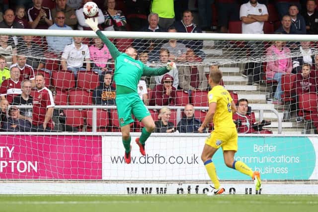 FULL-STRETCH: Adam Smith tips a shot over the bar during Wimbledon's visit to Sixfields earlier this season