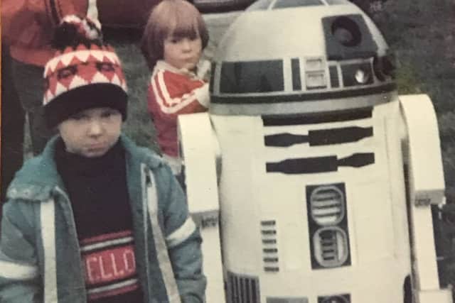 Children pose next to Star Wars character R2D2