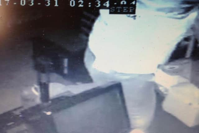 A burglar leaps over the counter at Mr Cruden's shop in St Giles before taking a haul of goods.
