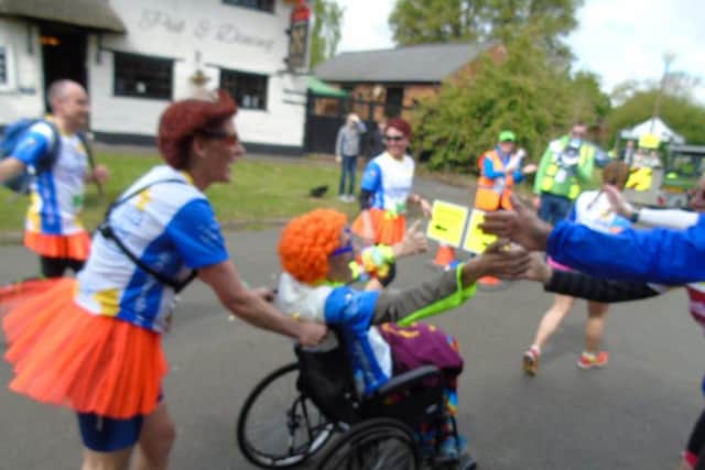 Dave high-fives supporters, pushed by his wife Paula.