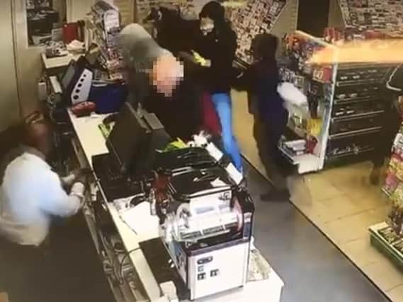 The three robbers burst into Ecton Brook Post Office on May 2. One of the gang has a gun pointed at shopkeeper Bipin Patel...