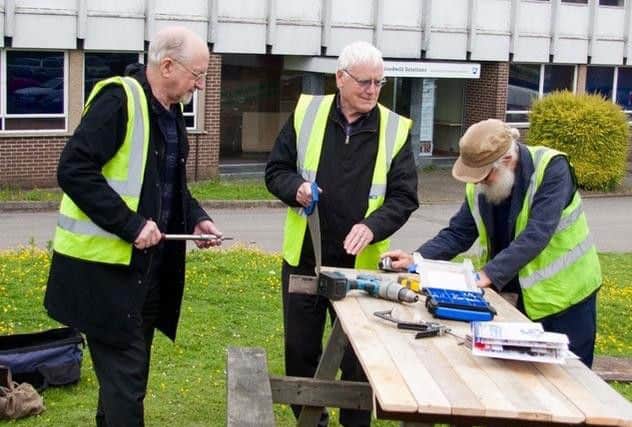 The Northampton Men's Sheds team work on a bench.