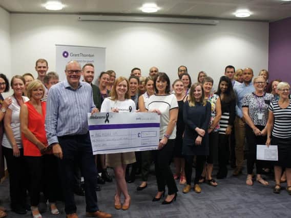 Staff at Grant Thornton in Northampton hand over the cheque to Melanoma UK