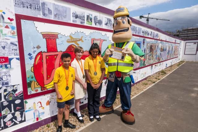 Pupils from Delapre Primary School with the hoarding featuring their artwork on the 'Waterside Express'