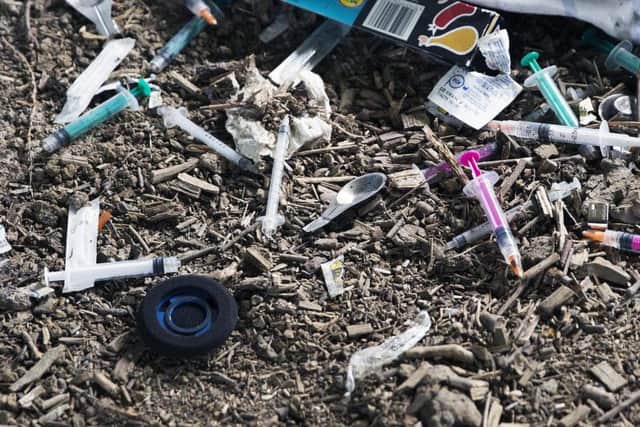 Syringes and metal spoons litter the archway near to a children's pocket park.
