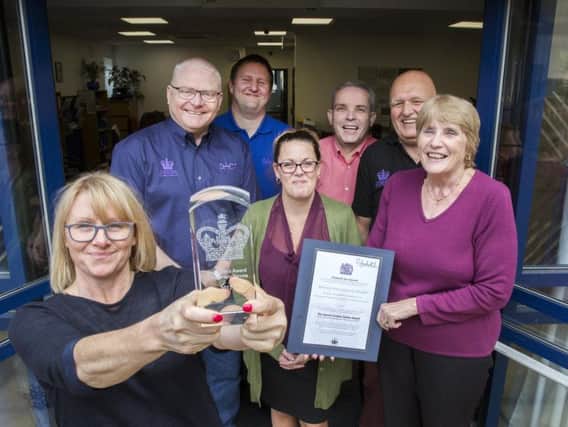 DACT workers proudly show off their Queen's Award for Voluntary Service at their Daventry headquarters. Picture: Kirsty Edmonds